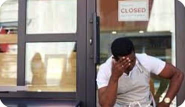A business owner standing outside a quiet storefront